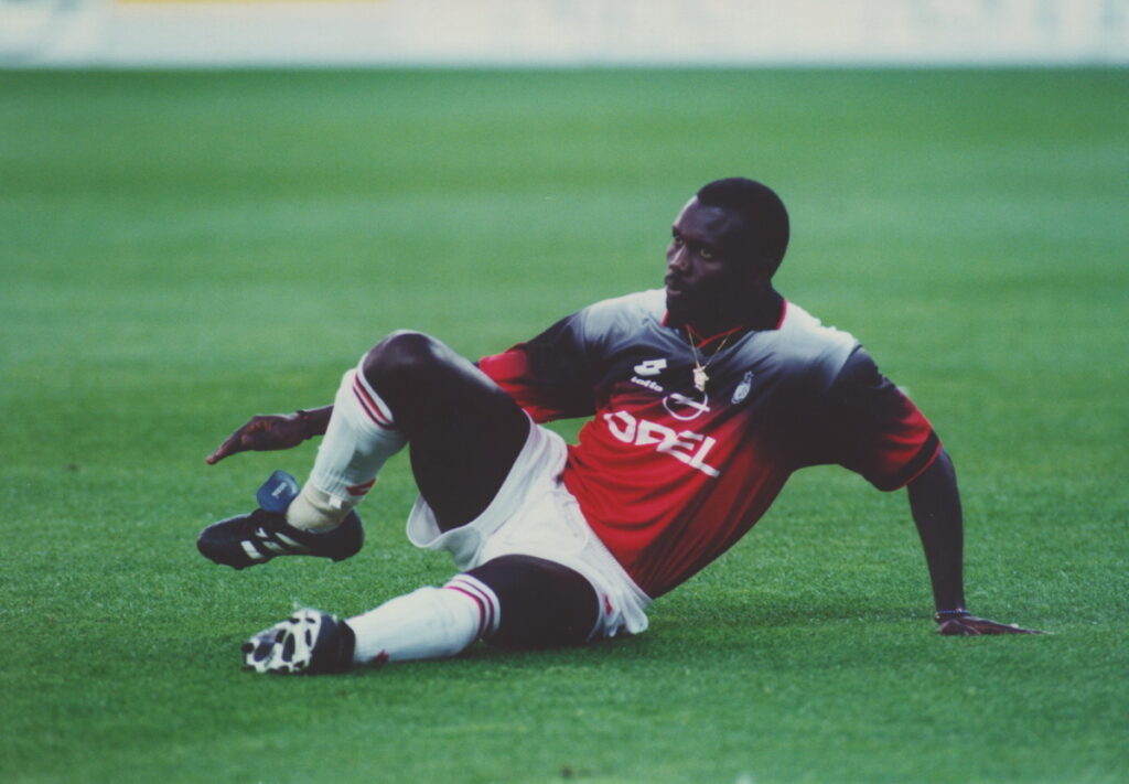 George Weah seduto in campo